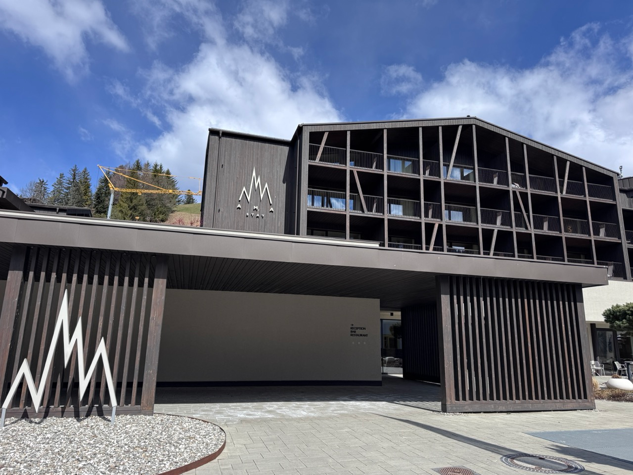 AMA Stay exterior entrance in San Vigilio with dark timber facade and mountain sky