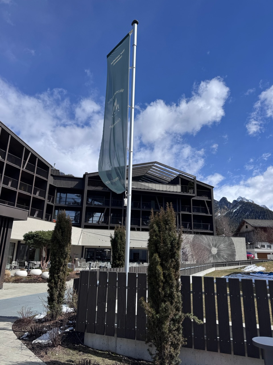 AMA Stay flag and hotel building with Dolomites peaks behind it