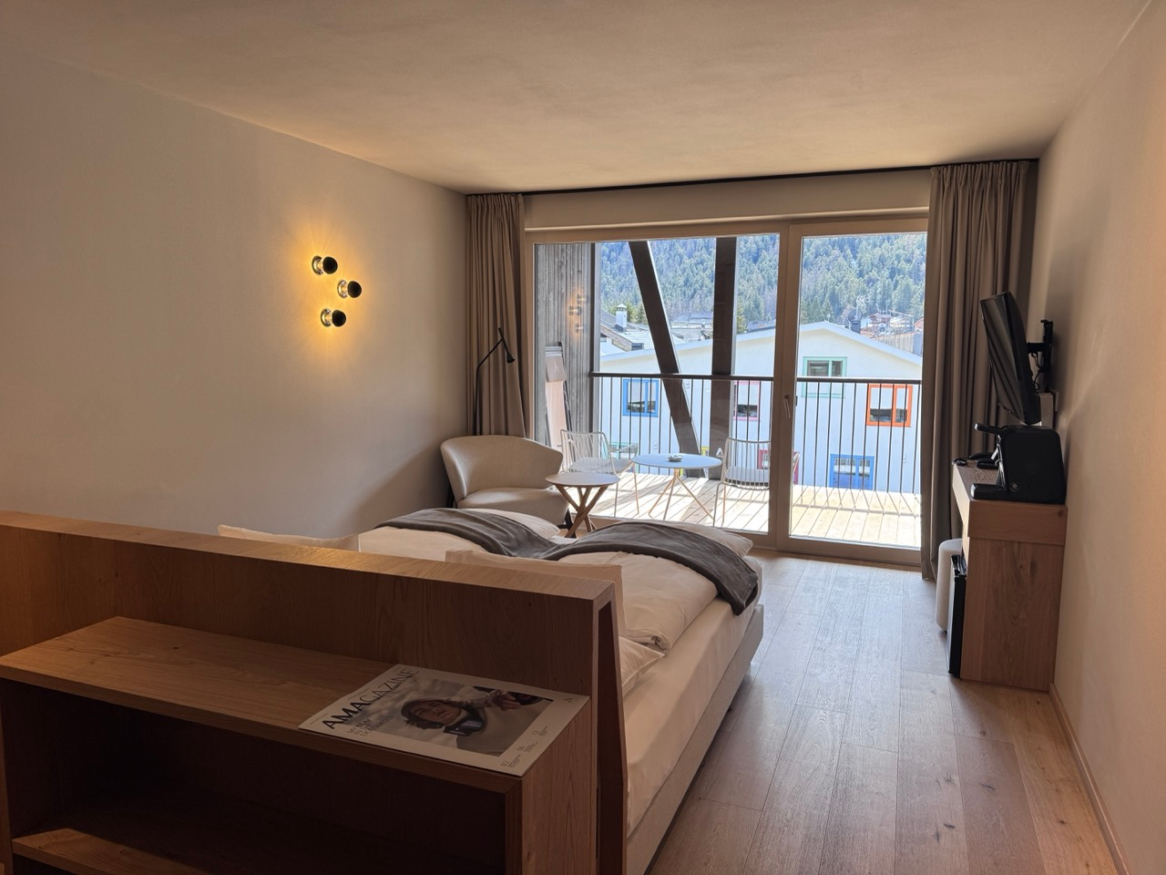 AMA Stay guest room with wood finishes, balcony doors, and mountain village view
