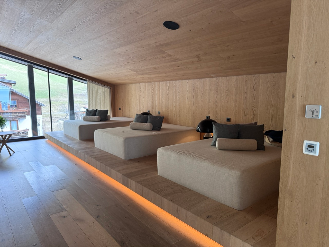 Wood-lined relaxation room at AMA Stay spa with loungers and large windows
