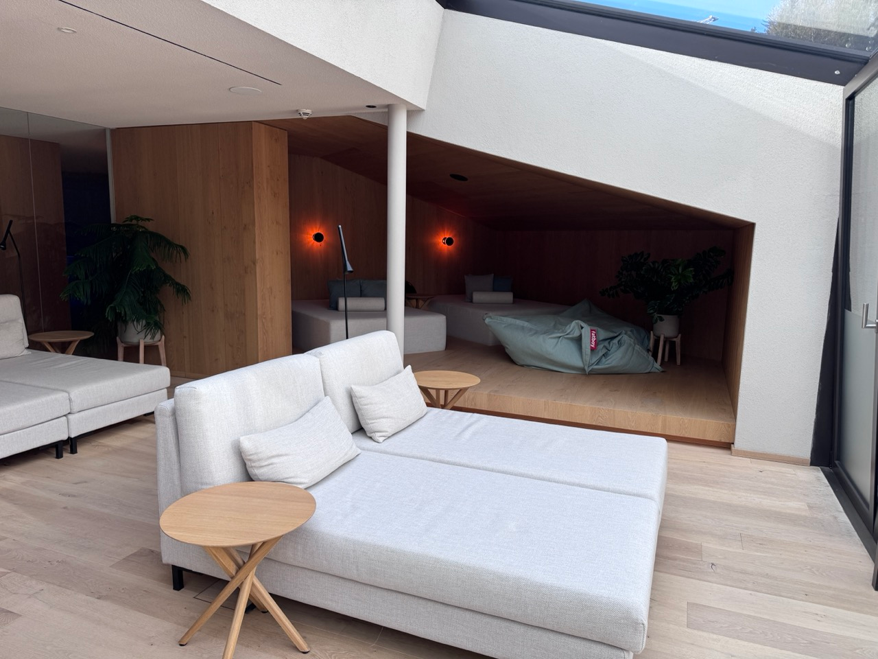 Quiet lounge area at AMA Stay with daybeds, warm wood alcoves, and plants