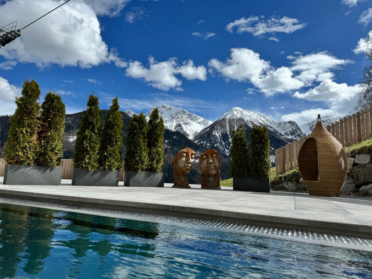 Heated outdoor alpine pool in winter with snow and Kronplatz slopes in the distance